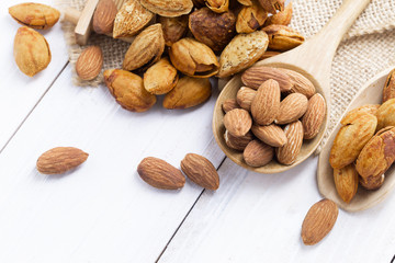 Almonds in a black bowl against dark rustic wooden background