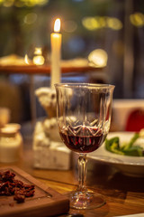 glass of red wine and candle on wooden table