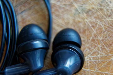 Close-up headphone stack on table, modern smartphone's earbuds device accessories