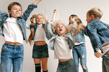 The portrait of cute little kids boy and girls in stylish jeans clothes looking at camera against...