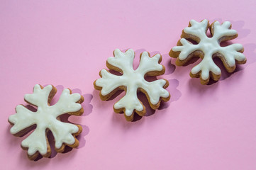 Christmas gingerbread on a pink background. Gingerbread snowflake covered with white icing.