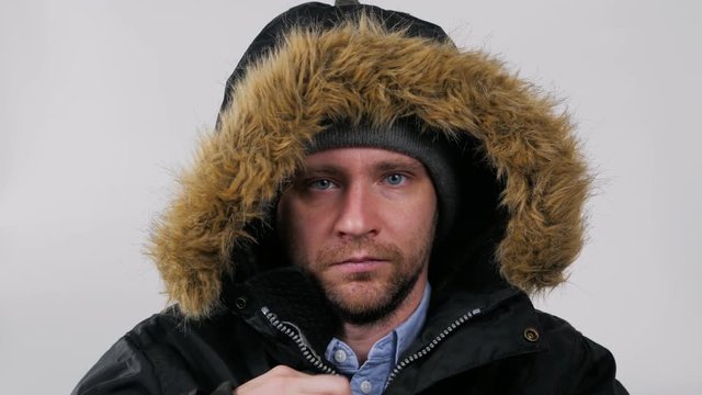 Handsome young man wearing a light winter parka jacket - smiling to the camera on isolated background zipper hood strong
