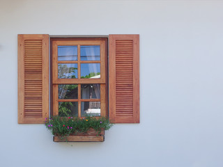 natural wood windowwith hanging flower decor on cement wall background.