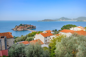 Fototapeta na wymiar Scenic view of Saint Stephen (Sveti Stefan) island in Adriatic sea connected with coast by bridge. Beautiful aerial photo of luxury resort on Adriatic sea.