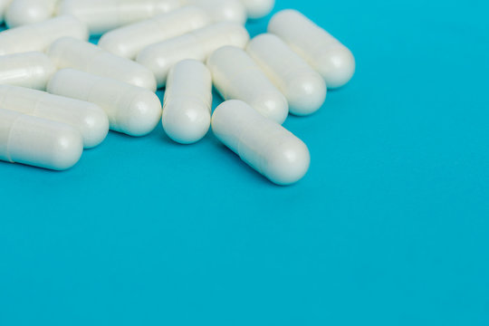 White capsules of medicine lie on a blue background.