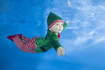 Little boy dressed as a gnome underwater on a blue water background.  Healthy family lifestyle and...