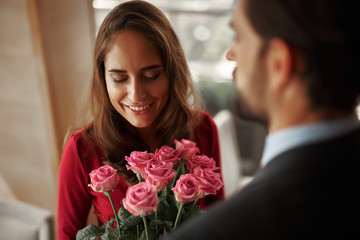 Concept of romantic celebration. Close up portrait of smiling beautiful lady getting bouquet of flowers from her male lover