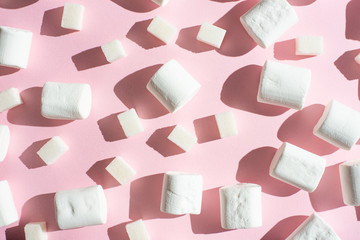 White marshmallows, with sugar cubes, on a pink background, with hard shadows. The ability to use...