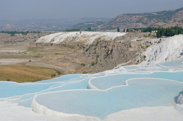 cotton castle in Pamukkale, Turkey. White limestone cliffs with water, against the sky