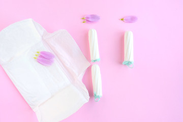 Kiev, Ukraine - 11.29.2018. Tampons with selective focus and petals on pink background. Woman hygiene for period days. Ginecology pads for menstrual mothly cycle. Protective care for woman health.