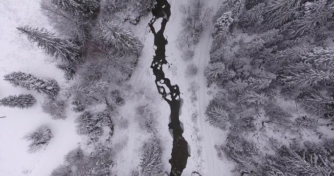 Aerial shooting. Very beautiful winter landscape. Snow covered mountains. Winter mountains. the camera flies forward and looks down. The camera flies along the mountain stream.