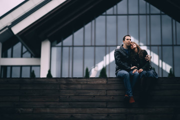  couple of beautiful people sitting embracing in the cold in the city. romantic meeting