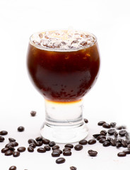 Ice black coffee in a clear glass on a white background with coffee beans.