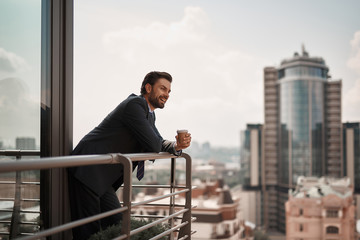 Take a pause. Full length portrait of cheerful businessman enjoying city view on office balcony...