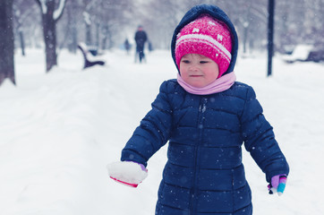 Fototapeta na wymiar Little girl walks on the street in the winter day