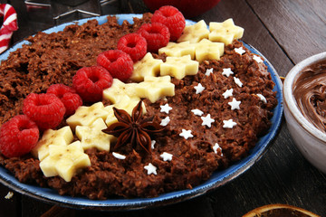 Bowl of cacao oatmeal porridge with banana, raspberries coconut and caramel sauce on rustic table, hot and healthy food for Breakfast