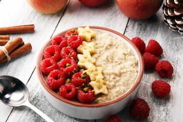 Bowl of oatmeal porridge with banana, raspberries coconut and caramel sauce on rustic table, hot and healthy food for Breakfast