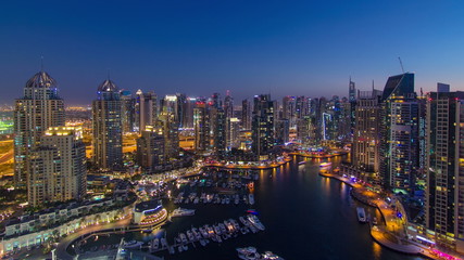 Fototapeta na wymiar Dubai Marina with yachts in harbor and modern towers from top of skyscraper transition from day to night timelapse