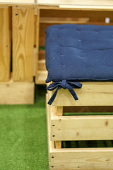Wooden stool with multicolored cushion.