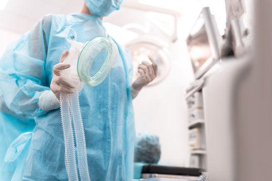 Doctor wearing medical uniform and holding a modern anesthetic mask in the operation theatre