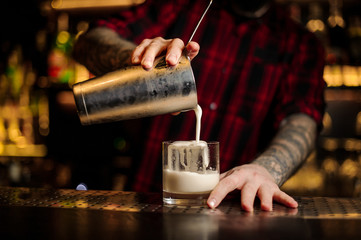 Fototapeta na wymiar Barman pouring fresh thick creamy alcoholic drink into a glass