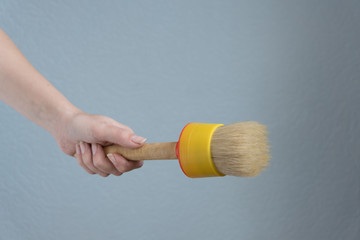 woman holding a big paint brush in her hand fro doing repairs.