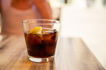 Glass of cola with ice and lemon on the table. Street cafe. Soft focus. Copy space