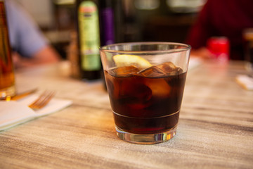 Glass of cola with ice and lemon on the table. Street cafe. Soft focus. Copy space