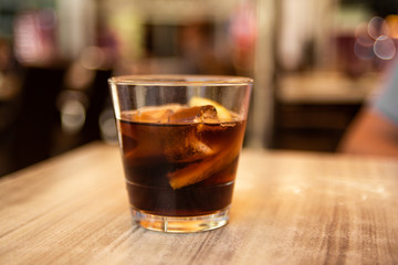 Glass of cola with ice and lemon on the table. Street cafe. Soft focus. Copy space