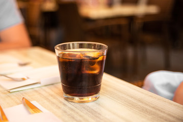 Glass of cola with ice and lemon on the table. Street cafe. Soft focus. Copy space