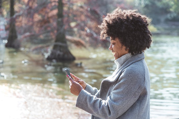 Portrait of attractive afro woman using mobile phone in the street