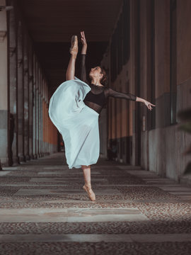 Young ballerina in skirt and blouse dancing in archway
