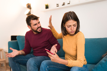 Couple arguing, having relationship problems. Boyfriend and girlfriend fighting, man yelling at woman while she is turning her head and holding phone. Divorce concept.