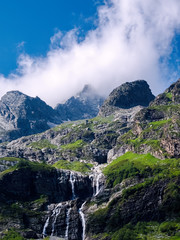 From the cloudy haze the summit peaks - Sofia, 3640m. On the slopes descend Sofia waterfalls, originating from the Sophia glacier. Arkhyz. KCR, Russia.