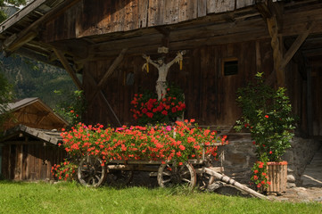 Fototapeta premium Kreuz und blumengeschmückter Leiterwagen im Ridnauntal