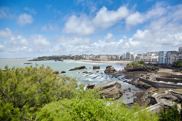 Fototapeta premium Cityscape of Biarritz, France: Old stone harbor, buildings and sandy beaches. Summer sunny day with blue sky and white clouds