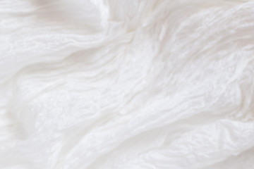 Obraz na płótnie Canvas White wrinkled old silk. Thin tissue. Air folds. Silk fabric texture blur background. Shabby chik, blured.