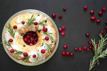 Homemade Christmas cake with garnish cranberry and rosemary on decorative plate. Top view .