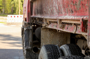 Fototapeta premium Closeup of old rusty and dirty truck side, paint peeling on cargo area wall, large tires visible, blurred road block sign id distance. Roadworks illustration.