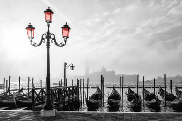 Black and white photo of gondolas in Venice at sunrise with Saint Giorgio island in morning fog, as seen from San Marco square © hungry_herbivore