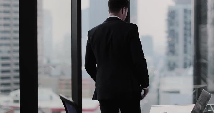 Businessman looking out at city skyline thinking