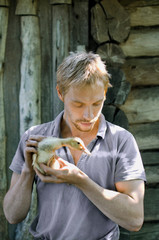 portrait of a young village man with a duckling in his hands