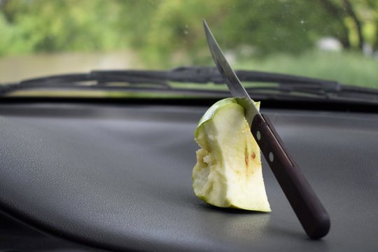 half-eaten apple with a knife lies in the car near the windshield