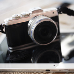 Compact digital photo camera on a wooden table with cup of coffee. Simple composition, soft focus