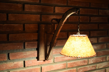 turning on an antique lamp on a red brick wall in a dark room