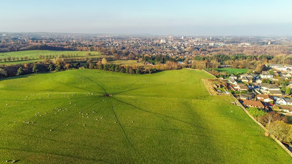 Fototapeta na wymiar Aerial image over a green field with grazing sheep to the townscape of Coatbridge.