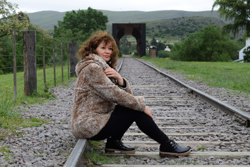 portrait of pretty woman resting on the railroad tracks in the afternoon