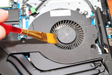 A geek cleans a laptop cooler. Contaminated computer cooling system. Technical support concept
