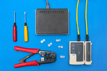 Cripmer tool, network cable tester and a switch router isolated on the blue background. Network...