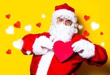 Funny Santa Claus have a joy and holding heart shape gift on yellow background
